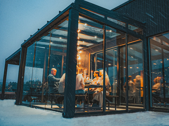 Innglasset crystal utestue i snø med koselig og varm belysning