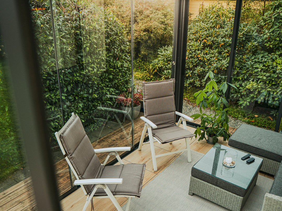 Pergolux Crystal Utestue omringet av planter i hagen. Koselig, friskt møte med naturen.